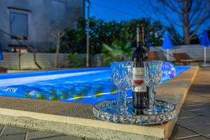 a bottle of wine and two glasses next to a pool at Villa Ninna in Vantačići