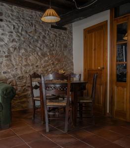 una mesa y sillas en una habitación con una pared de piedra en La Atalaya, en Hervás