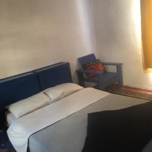 a bedroom with a bed and a blue chair at Chez Youssef in Merzouga