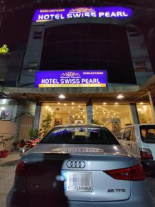 um carro estacionado em frente a um hotel, a menos que pérola em Hotel Swiss Pearl em Lahore
