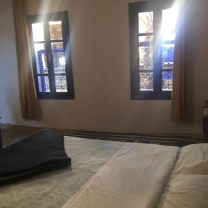 a bed in a room with two windows at Chez Youssef in Merzouga