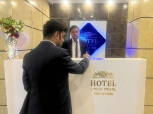 a man in a suit standing next to a hotel sign at Hotel Swiss Pearl in Lahore