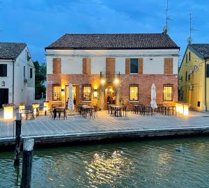 a building with tables and chairs on a dock next to the water at Locanda del Delta in Comacchio