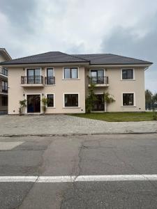 a large white house with a parking lot at Bloom Apartament in Alba Iulia