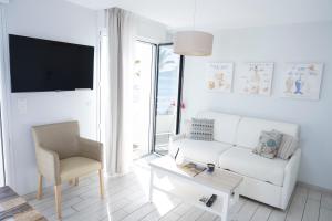 a living room with a white couch and a chair at Hotel La Ciotat - A deux pas de l'eau in La Ciotat