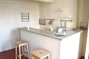 een keuken met een aanrecht en 2 krukken bij Studio des Cardeurs au coeur du centre historique in Aix-en-Provence