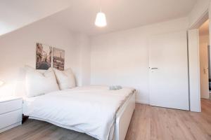 a white bedroom with a large bed with white sheets at Sehr schöne Wohnung für 6 Pers. in Bremen