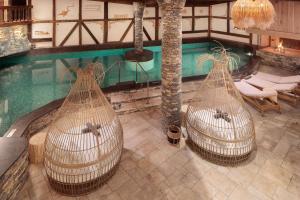 uma vista sobre uma piscina com redes de descanso de rattan em Aïda Hôtel & Spa - "Adults Only" Relais & Châteaux em Crans-Montana