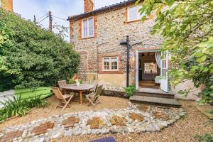 a garden with a table and chairs in front of a house at Quay Corner - Norfolk Cottage Agency in Cley next the Sea