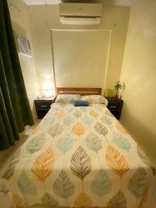 ein Schlafzimmer mit einem Bett mit einer Decke mit Blättern darauf in der Unterkunft Air-conditioned Home in Davao City
