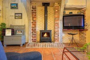 ein Wohnzimmer mit Kamin und Fernseher in der Unterkunft Gîte Les Toisnières in Marigné-Laillé