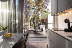 a kitchen with a table and a balcony with trees at Olivia apartamenti in Jūrmala
