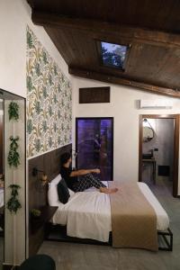 una donna seduta su un letto in una camera da letto di Nid’Amour suite&spa a Palermo