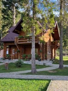 ein Blockhaus mit Bäumen davor in der Unterkunft База відпочинку „СІНАЙ“ in Sloboda