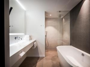 een witte badkamer met een bad en een wastafel bij Hotel Van der Valk Maastricht in Maastricht