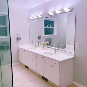 Baño blanco con lavabo y espejo en Quiet Three Bedrooms House, en Victoria