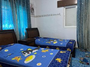 two beds in a room with blue sheets with cartoons on them at Jad apartment in Irbid