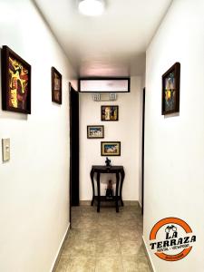 un pasillo con una mesa y cuadros en las paredes en Hostal La Terraza en Quito