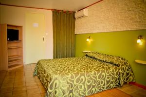 a bedroom with a bed and a green wall at Hotel Les Pins in Hourtin