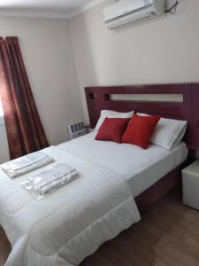 um quarto com uma grande cama branca com almofadas vermelhas em ALBERDI centro MENDOZA em Mendoza