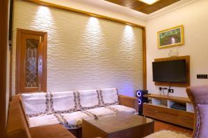 Galaxy Stay Casa في Bhowāli: غرفة معيشة مع أريكة وتلفزيون بشاشة مسطحة