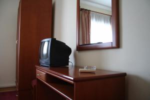une télévision assise au-dessus d'une commode avec un miroir dans l'établissement Residencial Dom Duarte, à Viseu