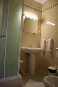 La salle de bains est pourvue d'un lavabo et d'un miroir. dans l'établissement Residencial Dom Duarte, à Viseu