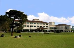 a large building with a tree in the middle of a field at Damyang Spa and Tourist Hotel in Damyang