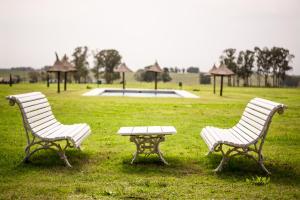 dos bancos y una mesa en un campo en Hotel Santa Cristina, en Durazno