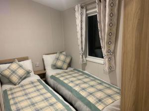Un dormitorio pequeño con dos camas y una ventana. en Southview Holiday Park, Deluxe Caravan, en Skegness