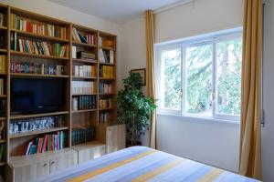 een slaapkamer met boekenplanken, een televisie en een raam bij AURELIA LORIS HOUSE in Rome
