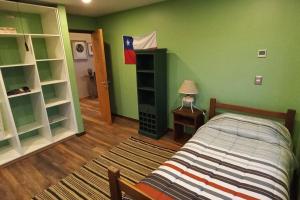 1 dormitorio con cama y pared verde en TuArriendoCL-Llanquihue CondWerner Casa con Acceso a Hermosa Laguna, en Llanquihue
