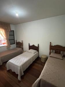 a bedroom with two beds and a window at Guest House da Cris in Itabira