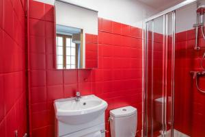 La salle de bains rouge est pourvue de toilettes et d'un lavabo. dans l'établissement Studio au cœur du Marais - II, à Paris