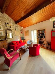 una sala de estar con muebles de color rojo y una pared de piedra. en Entre théâtre et Rhône, 87 m2 terrasse clim wifi Arles Camargue, en Arles
