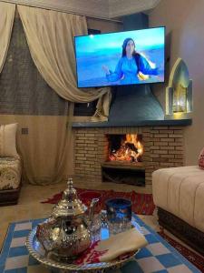 a living room with a fireplace with a tv above it at Riad Timskrine in Marrakech