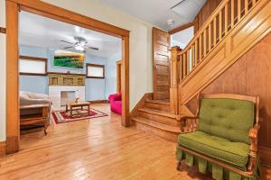 ein Wohnzimmer mit einer Treppe und einem grünen Stuhl in der Unterkunft Enchanting Echoes: Oasis Near the Falls in Niagara Falls