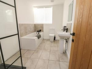 a bathroom with a tub and a toilet and a sink at The Church in Holyhead +12 photos