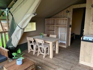 EesにあるCamping de Zeven Heuveltjesのテント付きの客室で、テーブルと椅子が備わります。