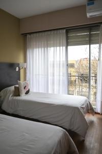 a bedroom with two beds and a large window at Hotel San Carlos in General Juan Madariaga