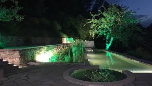 una piscina por la noche con luces verdes en Villa Fortezza Antique Rooms, en Ascoli Piceno