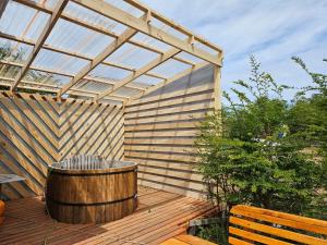 una terraza de madera con bañera de hidromasaje y pérgola en Hermosa cabaña con orilla de playa y tinaja en Lago Frío en Coihaique