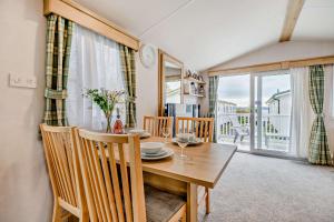 a dining room with a table and chairs and a window at Sea La Vie Lodge, Rockley Park Holiday Park, Poole, Dorset in Poole