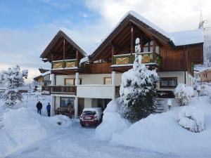 a snow covered house with people standing in front of it at Piz Apart Raich in Arzl im Pitztal