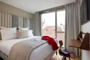 um quarto de hotel com uma cama e uma grande janela em Hôtel Pilgrim em Paris