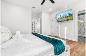a white bedroom with a large bed and a tv on the wall at Bold Bright 4BR3.5FULL BATHS Near Riverwalk Dtown in San Antonio