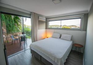 1 dormitorio con 1 cama y balcón con vistas. en Suítes com Vista Espetacular da Lagoa da Conceição, en Florianópolis