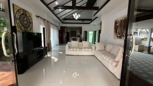 ein Wohnzimmer mit weißen Sofas und einem Flachbild-TV in der Unterkunft Cozy Villa Tai in Na Jomtien