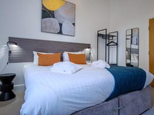 a bedroom with a large white bed with orange pillows at The Theobold Suite Stone Cross Mansion in Ulverston