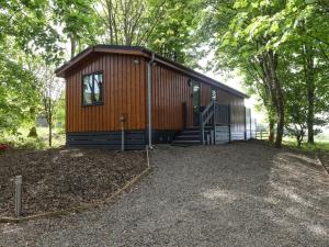 a small wooden cabin with a staircase next to trees at 1 bed in Langbank 73845 in Langbank